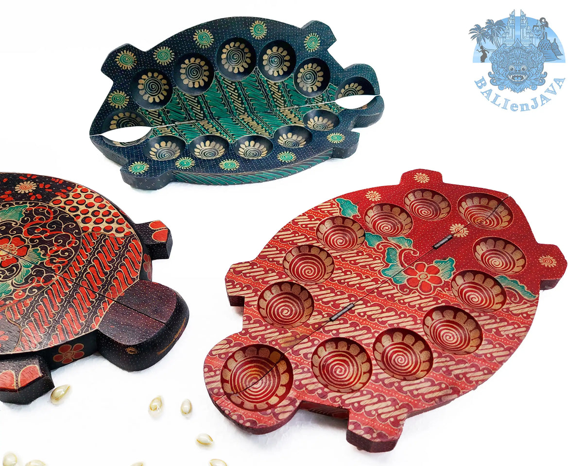 Three turtle-shaped wooden mancala board games with hand-painted details, displayed on a white background with small scattered cowrie shells.