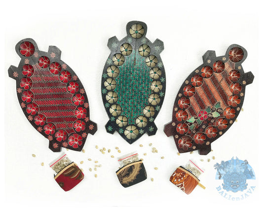 Three turtle-shaped mancala board game on a white background in showing circular pits, each painted with small flowers. Three small coin purse at the bottom with cowrie shells scattered nearby.