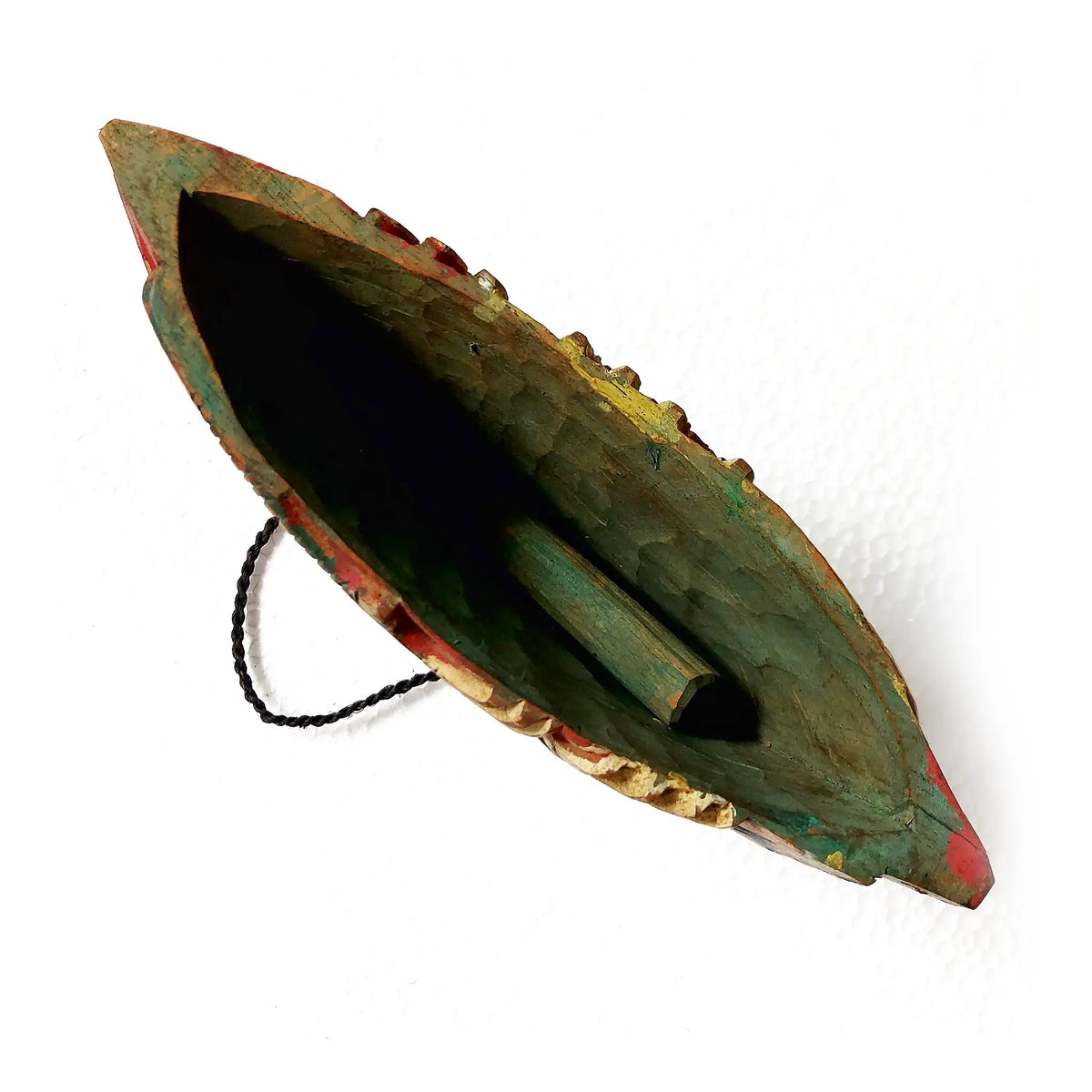 A hand-carved wooden bell with a dark green, red, and gold painted finish, featuring a black hanging cord and wooden clapper, shown on a white background.