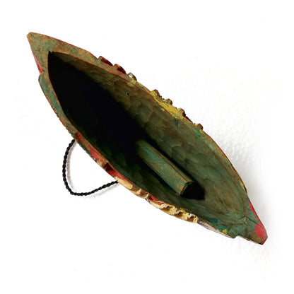 A hand-carved wooden bell with a dark green, red, and gold painted finish, featuring a black hanging cord and wooden clapper, shown on a white background.