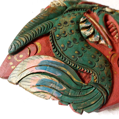 A close-up of a hand-carved wooden bell depicting a stylized dragon serpentine body, showcasing intricate hand-painted details in green, red, gold, and beige on a white background.