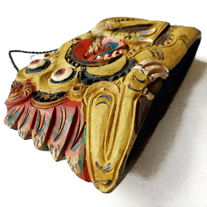 A hand-carved Asian style wooden bell, painted with yellow, red, blue, and black painted details, shown on a white background.