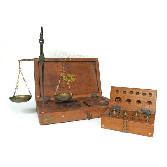 A vintage brass balance scale set with wooden box, shown with a smaller matching case containing brass weights, photographed on a white background.