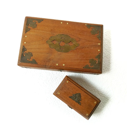 Two wooden boxes with oriental style brass corner guards and central medallion hardware, displayed on a white background.