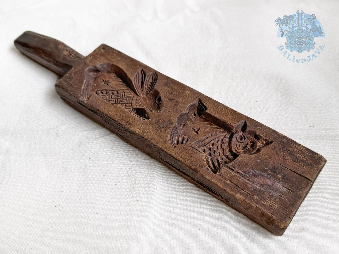 Old wooden cookie mold with rabbit and cat designs on a white background