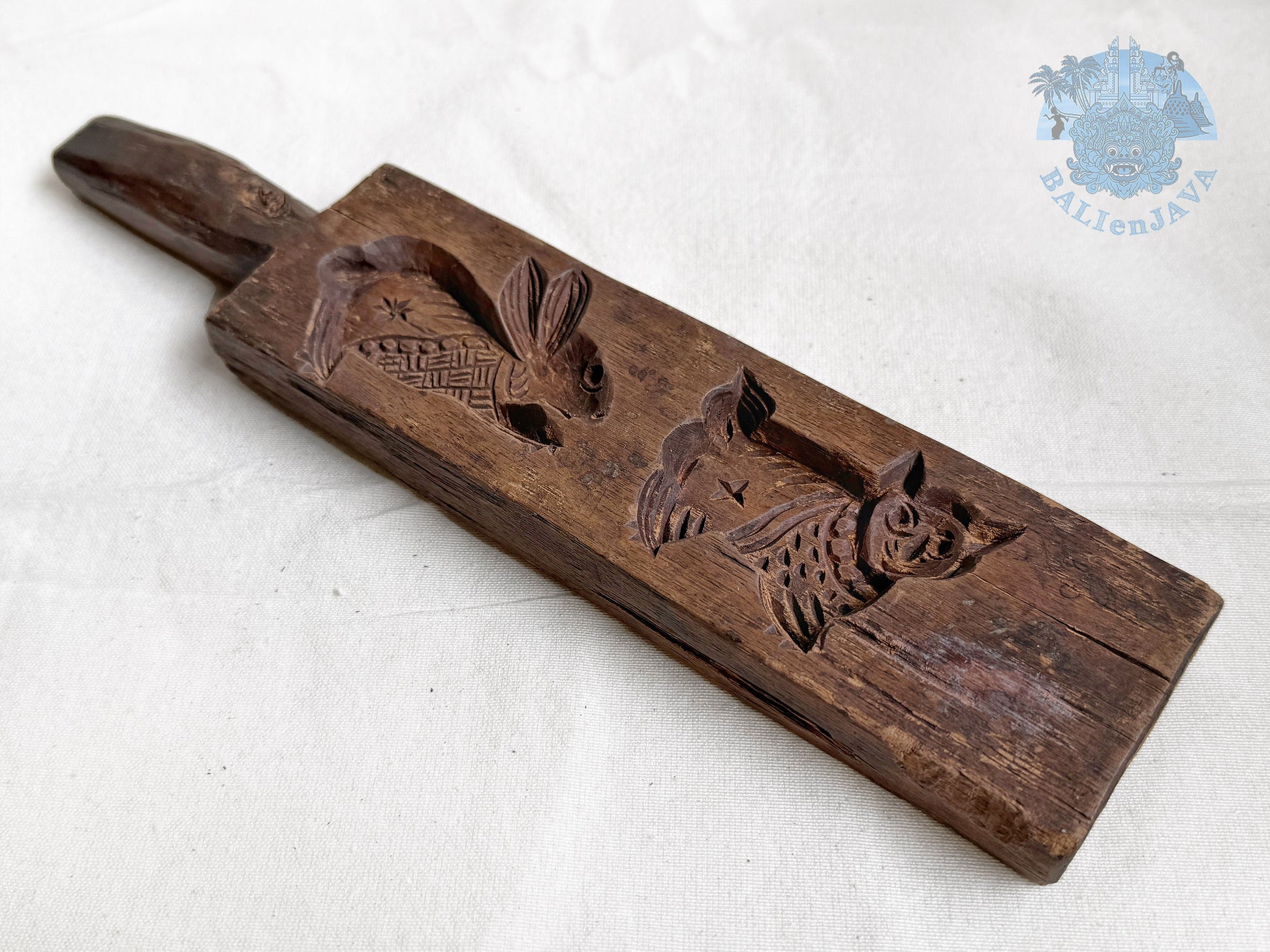 Old wooden cookie mold with rabbit and cat designs on a white background