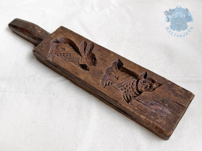 Old wooden cookie mold with rabbit and cat designs on a white background