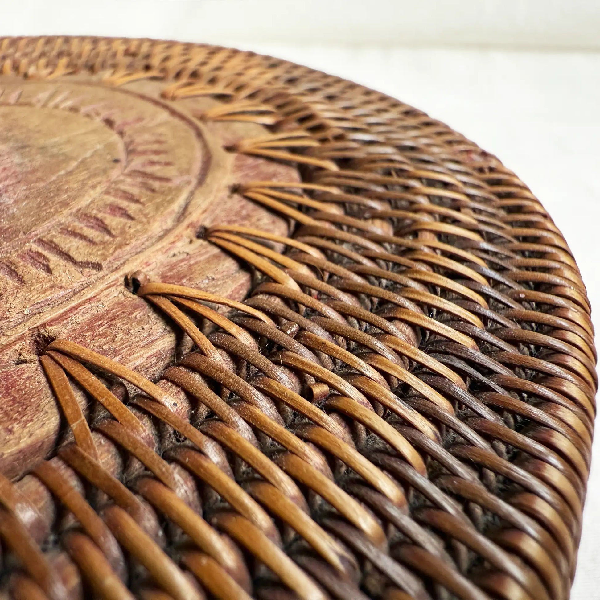Close-up of a round woven basket surface with a carved wooden top in warm brown.