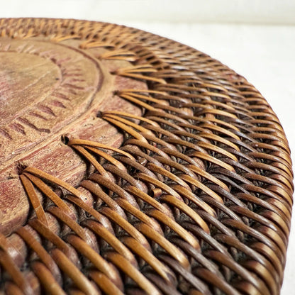 Close-up of a round woven basket surface with a carved wooden top in warm brown.