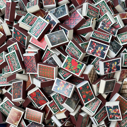A dense pile of vintage matchboxes with floral and batik patterns.