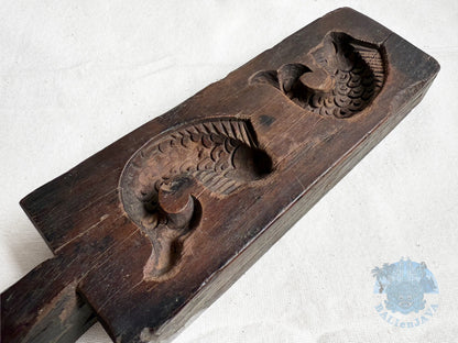 Wooden mold with two fishes design on a white background