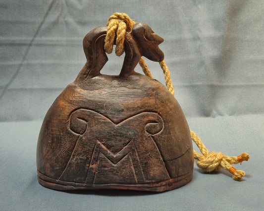 Wooden bell with carvings and a rope on a gray background