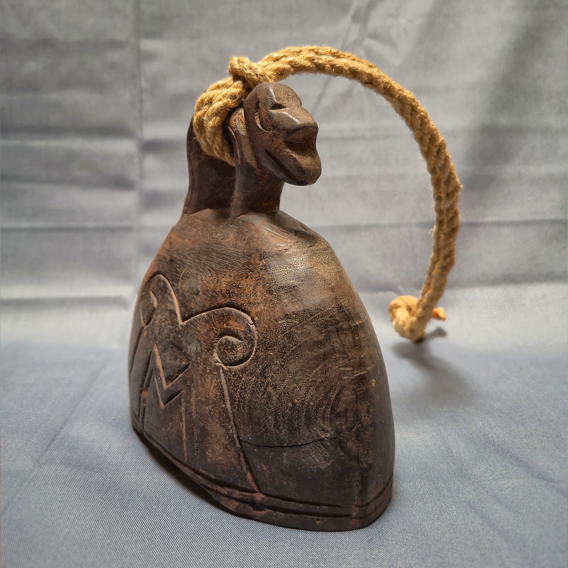 Wooden bell with rope on a gray background